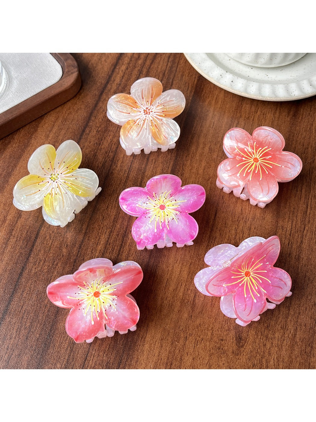 Beau floral claw clip held in hand showing translucent acetate material and detailed petals