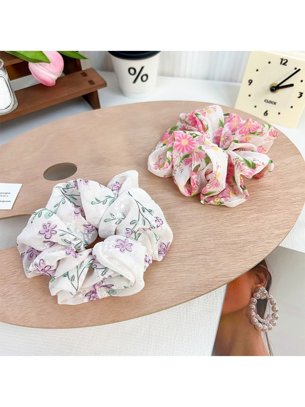 Gifty floral scrunchie worn on a wrist, showcasing ruffled design and bow accent