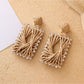 Earedge raffia square drop earrings displayed on a wooden surface