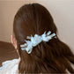 Beau banana clip displayed open to show the clasp mechanism and butterfly embellishments