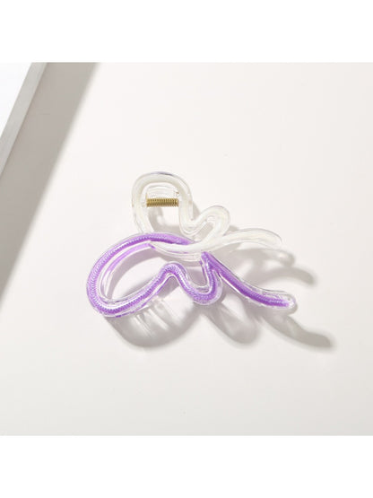 Butterfly hair clip with soft pastel hues on a light fabric background