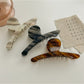 Beau chic acetate claw clip holding a section of brown hair