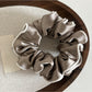 Detailed shot of the ruffled edges and shiny satin material of the scrunchie