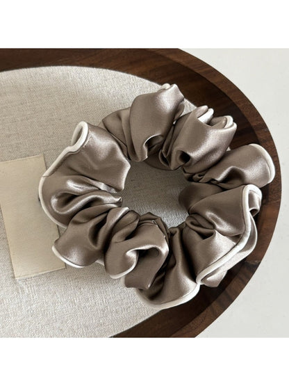 Detailed shot of the ruffled edges and shiny satin material of the scrunchie