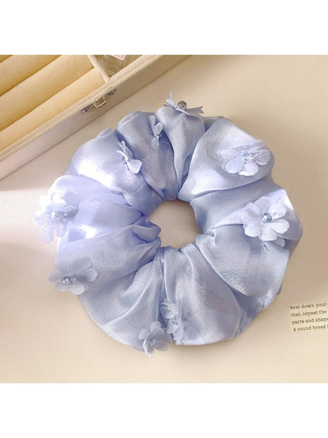 Gifty ruched scrunchie wrapped around a ponytail with visible floral accents
