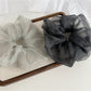Pink polka dot tulle scrunchie displayed on a white background