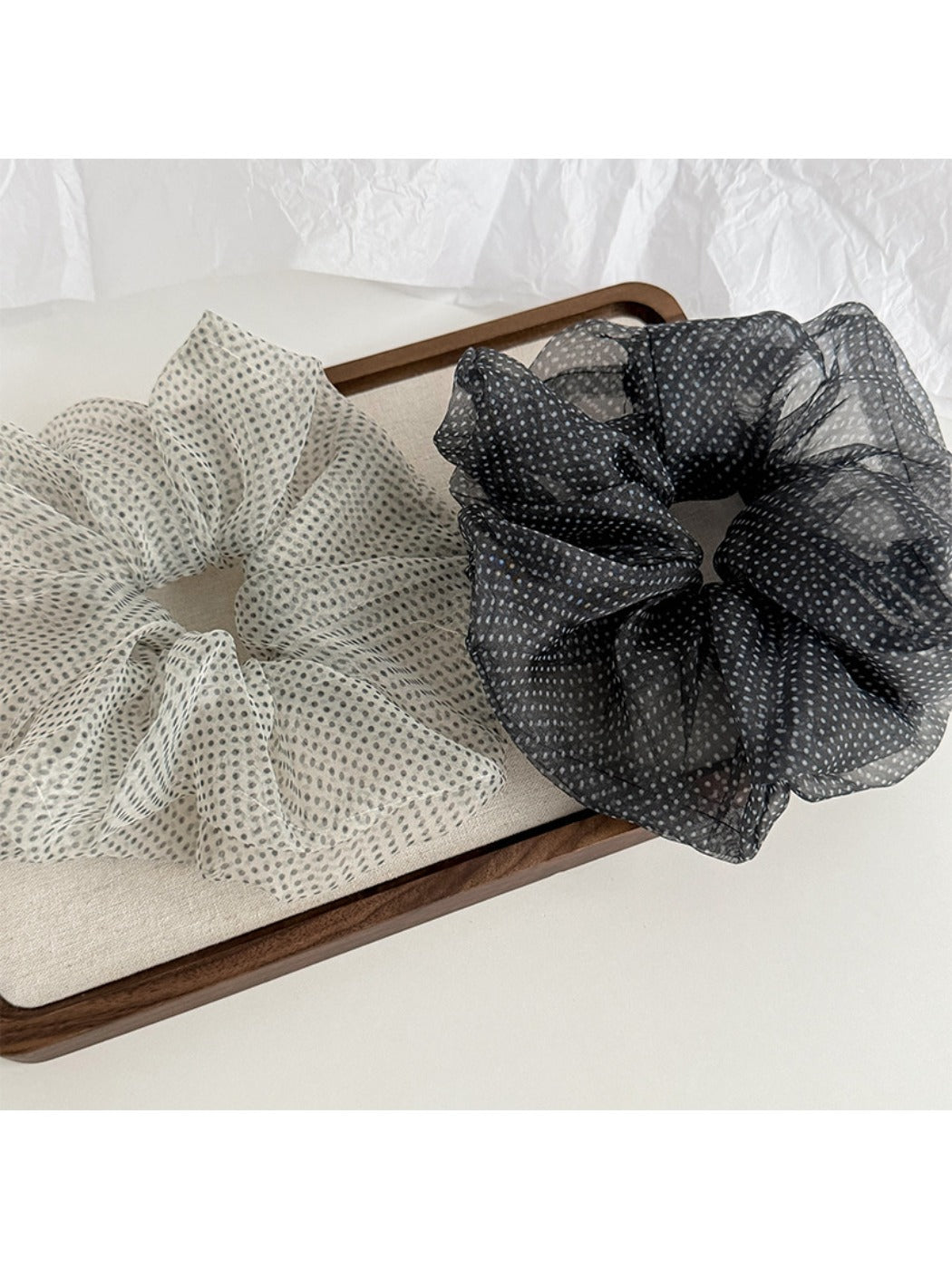 Pink polka dot tulle scrunchie displayed on a white background