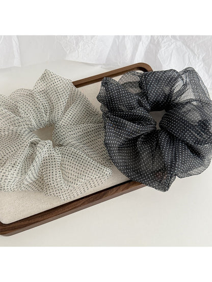 Pink polka dot tulle scrunchie displayed on a white background