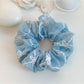 Blue bow print scrunchie stretched to show elastic inside