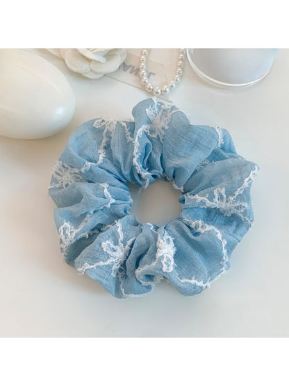 Blue bow print scrunchie stretched to show elastic inside