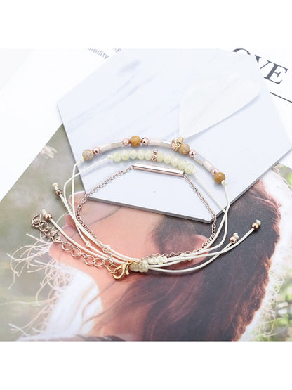 Lovra feather pendant small bead bracelet worn on wrist with natural lighting