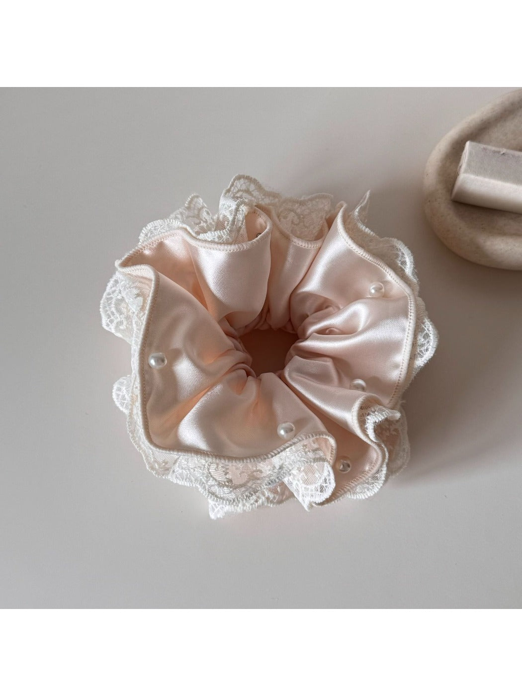 Beige satin scrunchie with lace trim shown from above
