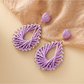 Bohemian style raffia earrings hanging from a jewelry stand