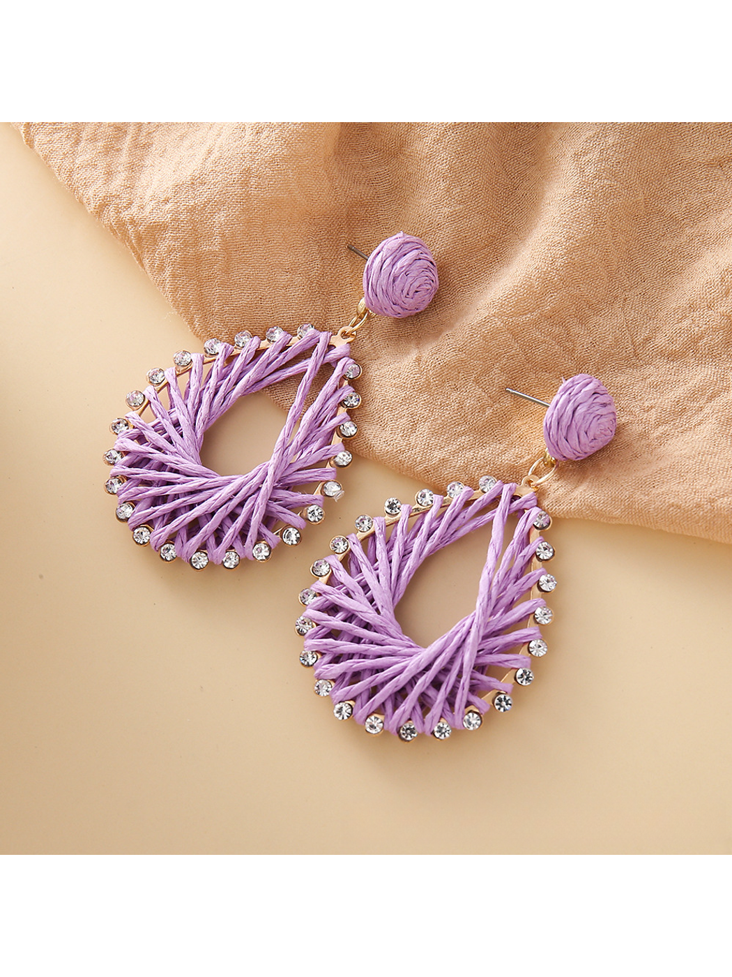 Bohemian style raffia earrings hanging from a jewelry stand