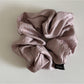 Vintage pleated fabric scrunchie on a wooden surface with natural lighting