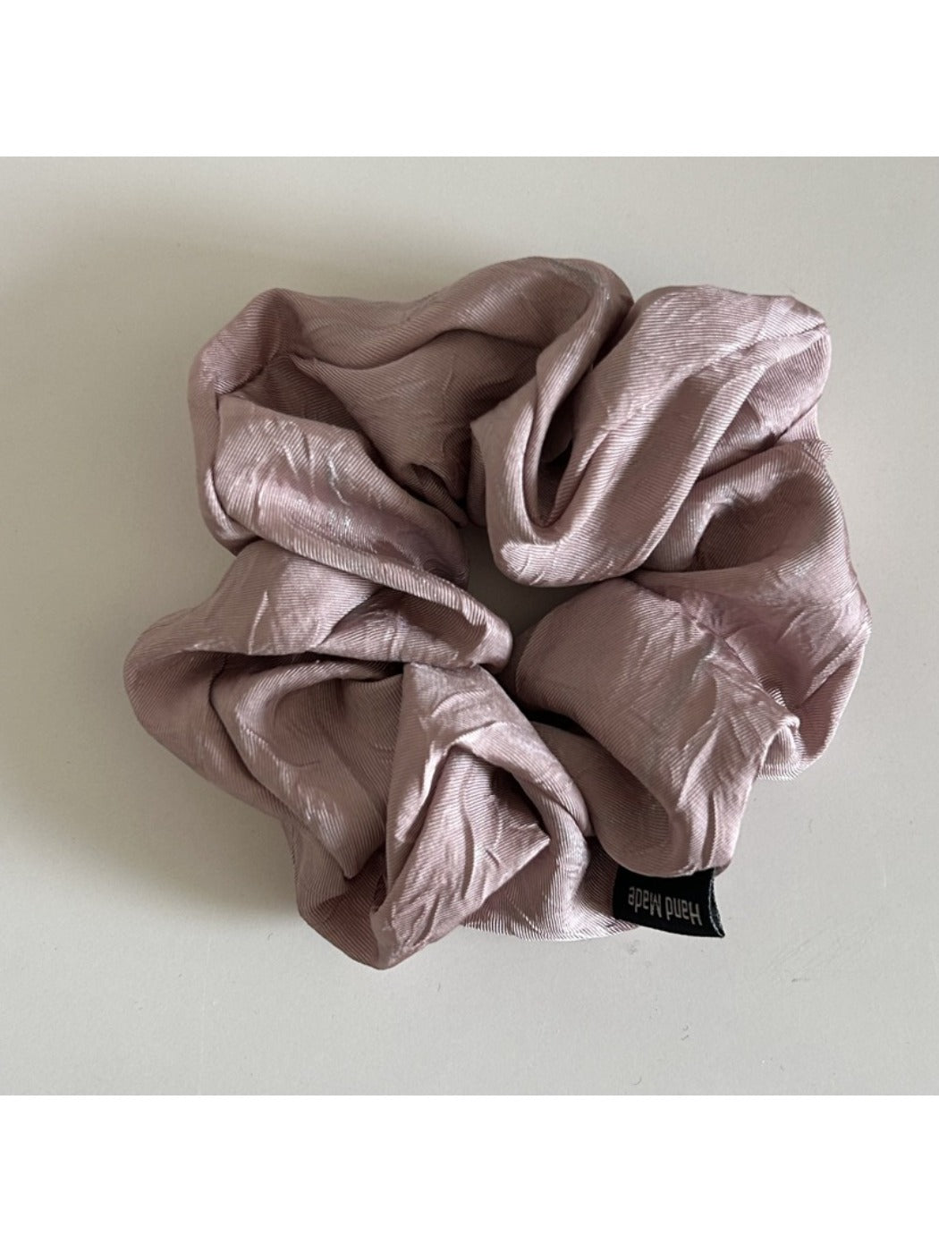 Vintage pleated fabric scrunchie on a wooden surface with natural lighting