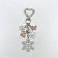 Snowflake pendant keychain attached to a set of keys on a white table