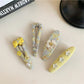 Yellow hair clip with tiny floral design clipped onto light brown hair
