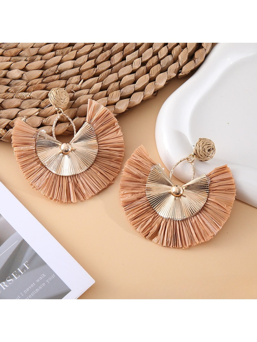 Side view of raffia fan earrings showing woven texture and gold hooks