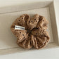 Soft fabric scrunchie with chic dot cutout pattern on neutral background