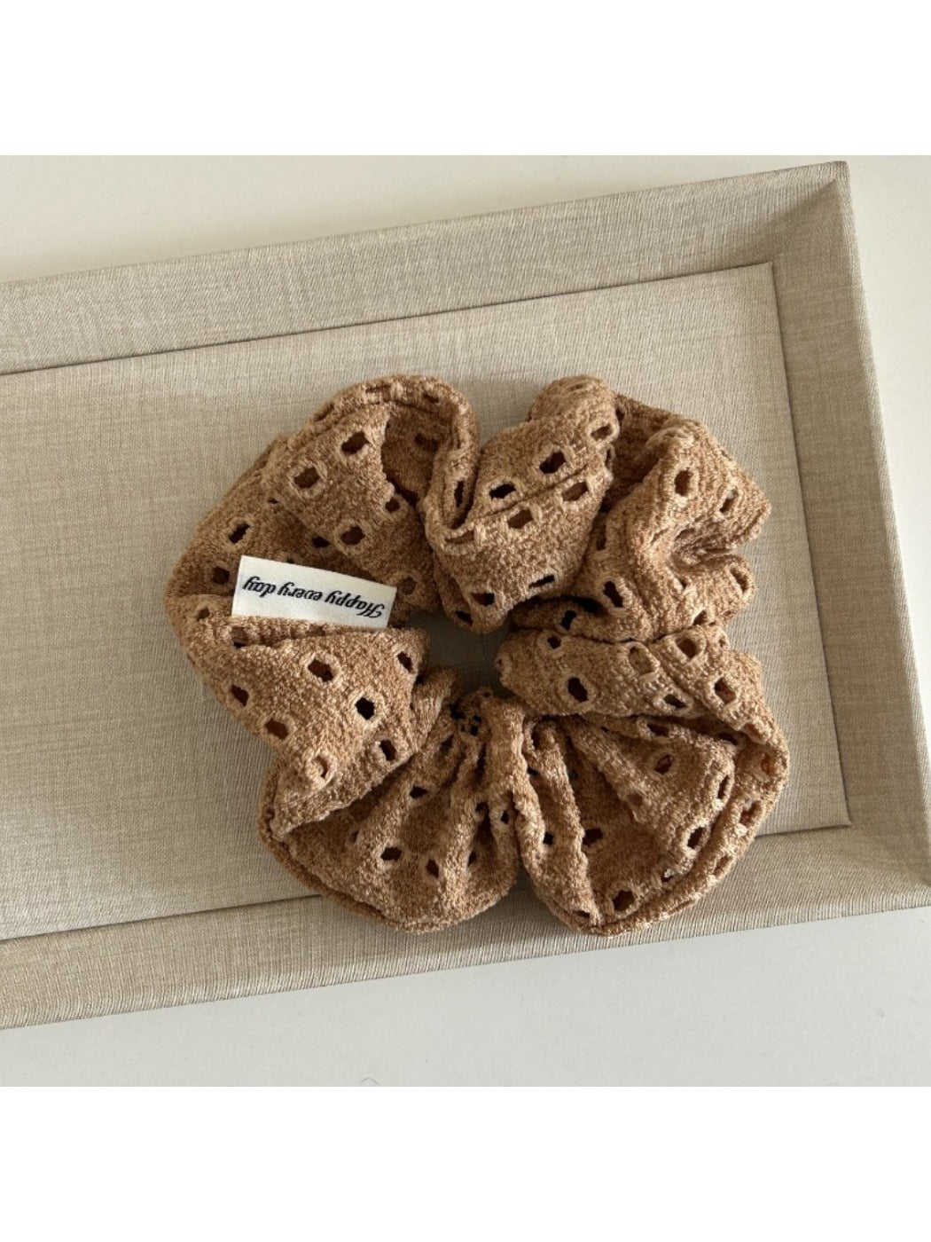 Soft fabric scrunchie with chic dot cutout pattern on neutral background