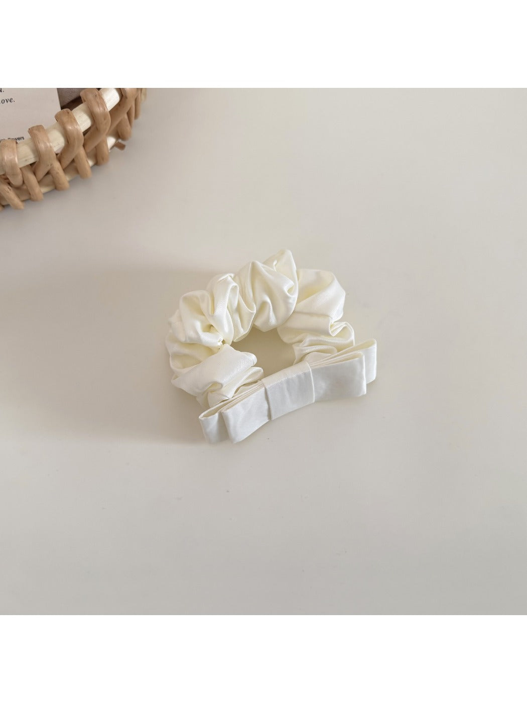 Model tying hair with the minimalist satin bow scrunchie in a low ponytail