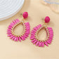 Lifestyle image of woman wearing oval raffia drop earrings with casual outfit