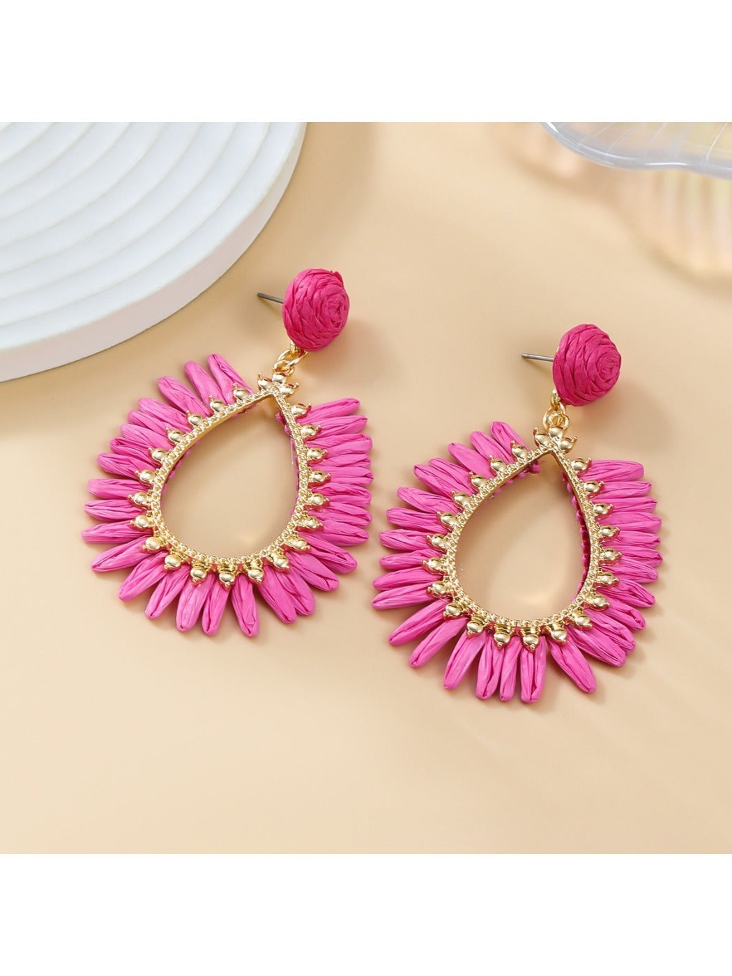Lifestyle image of woman wearing oval raffia drop earrings with casual outfit