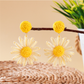 Bohemian daisy floral raffia stud earrings worn on ear with natural lighting