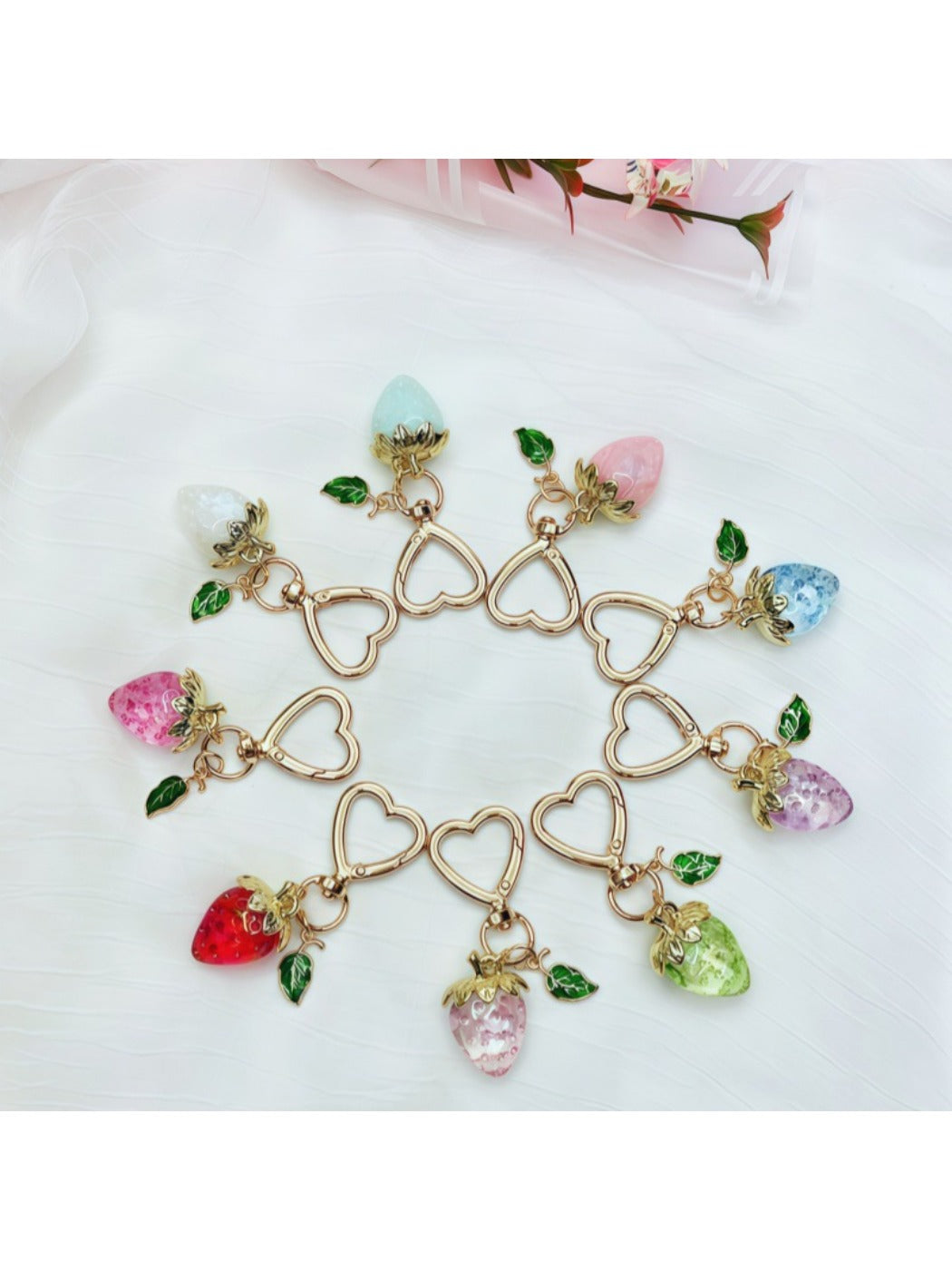 Keypus strawberry charm keychain hanging from a set of keys on wooden surface