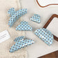 Blue hair claw clip with white polka dots on a white background
