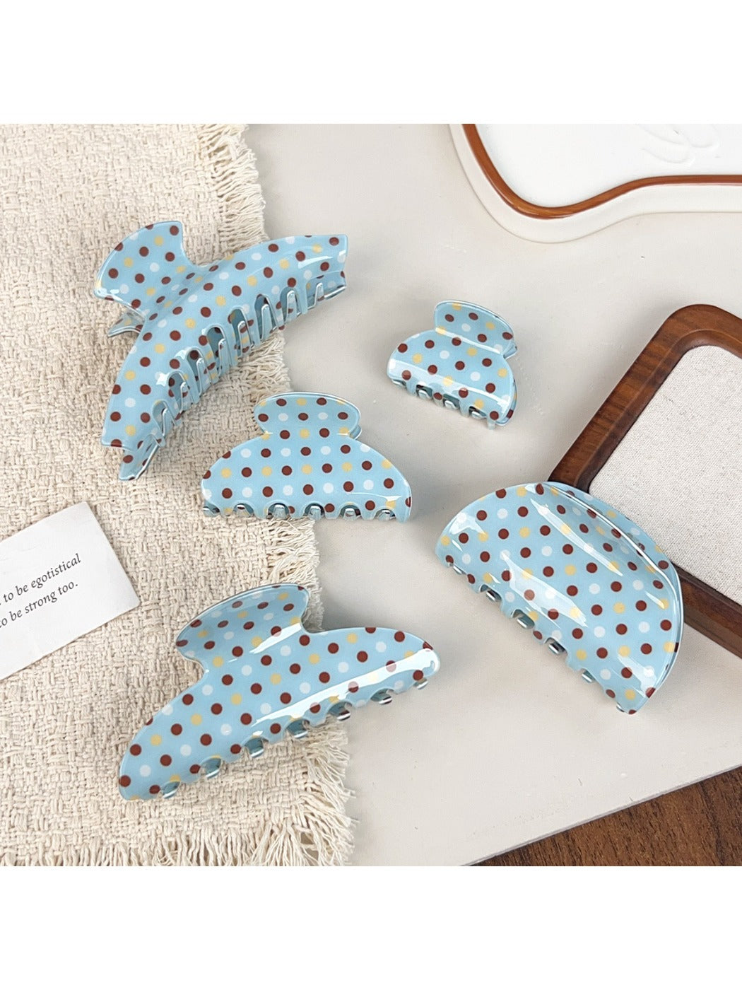 Blue hair claw clip with white polka dots on a white background