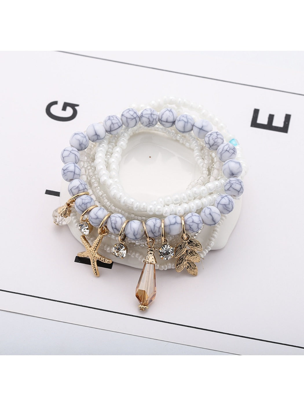 Lovra bracelet displayed on white background showing blue and white beads with ocean charm