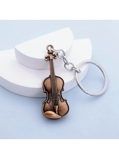 Guitar keychain attached to a set of keys on a wooden surface