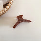 Beau polka dot acetate hair clip styled in brown hair, securing a section
