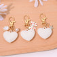 Heart shaped bag charm keychain attached to a handbag strap in natural light