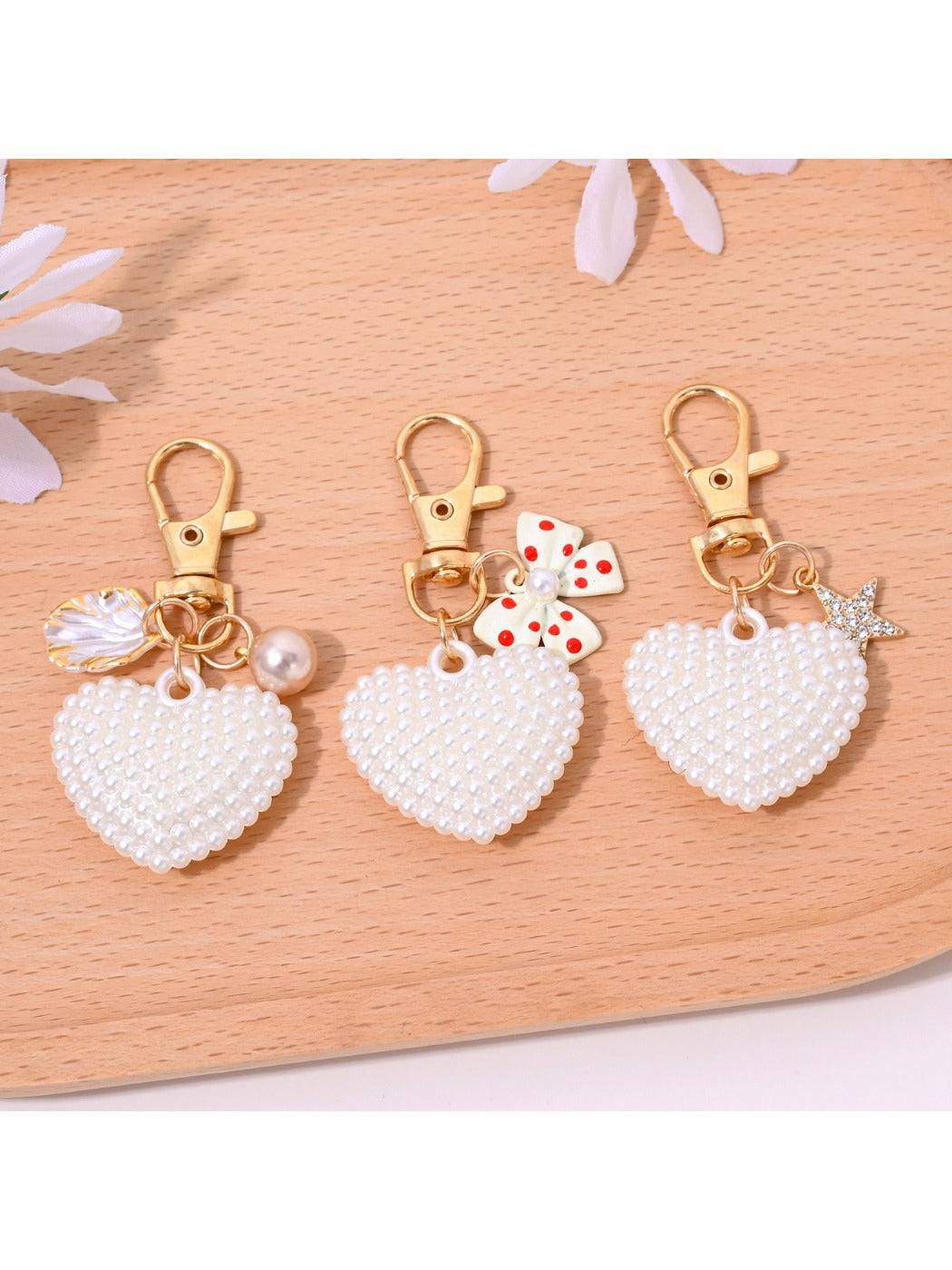 Heart shaped bag charm keychain attached to a handbag strap in natural light