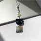 Blue eyed black cat keychain displayed on a white background