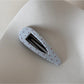 Beau hair clip with white polka dots on pink fabric background