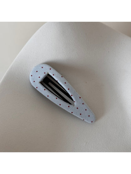 Beau hair clip with white polka dots on pink fabric background