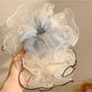 Beige tulle scrunchie styled on a wrist with soft folds and gathered fabric