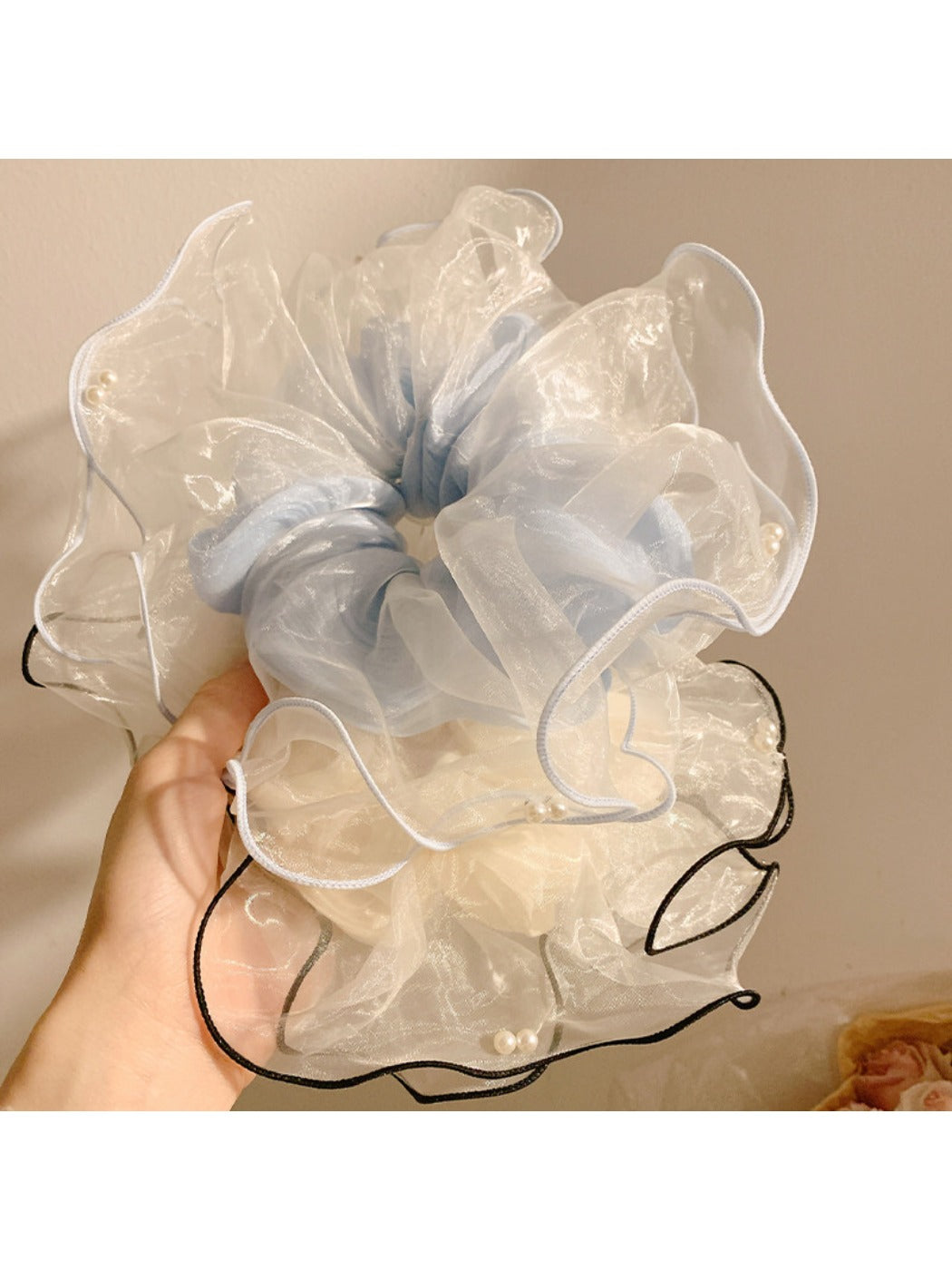 Beige tulle scrunchie styled on a wrist with soft folds and gathered fabric
