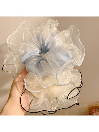 Beige tulle scrunchie styled on a wrist with soft folds and gathered fabric