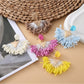 Close-up of stylish fan-shaped raffia drop earrings on white background