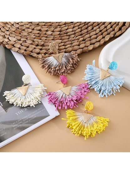 Close-up of stylish fan-shaped raffia drop earrings on white background