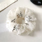 Close-up of a dainty white floral scrunchie with delicate flower patterns on fabric