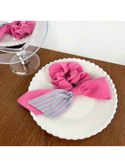 Magenta striped scrunchie next to matching hair accessories
