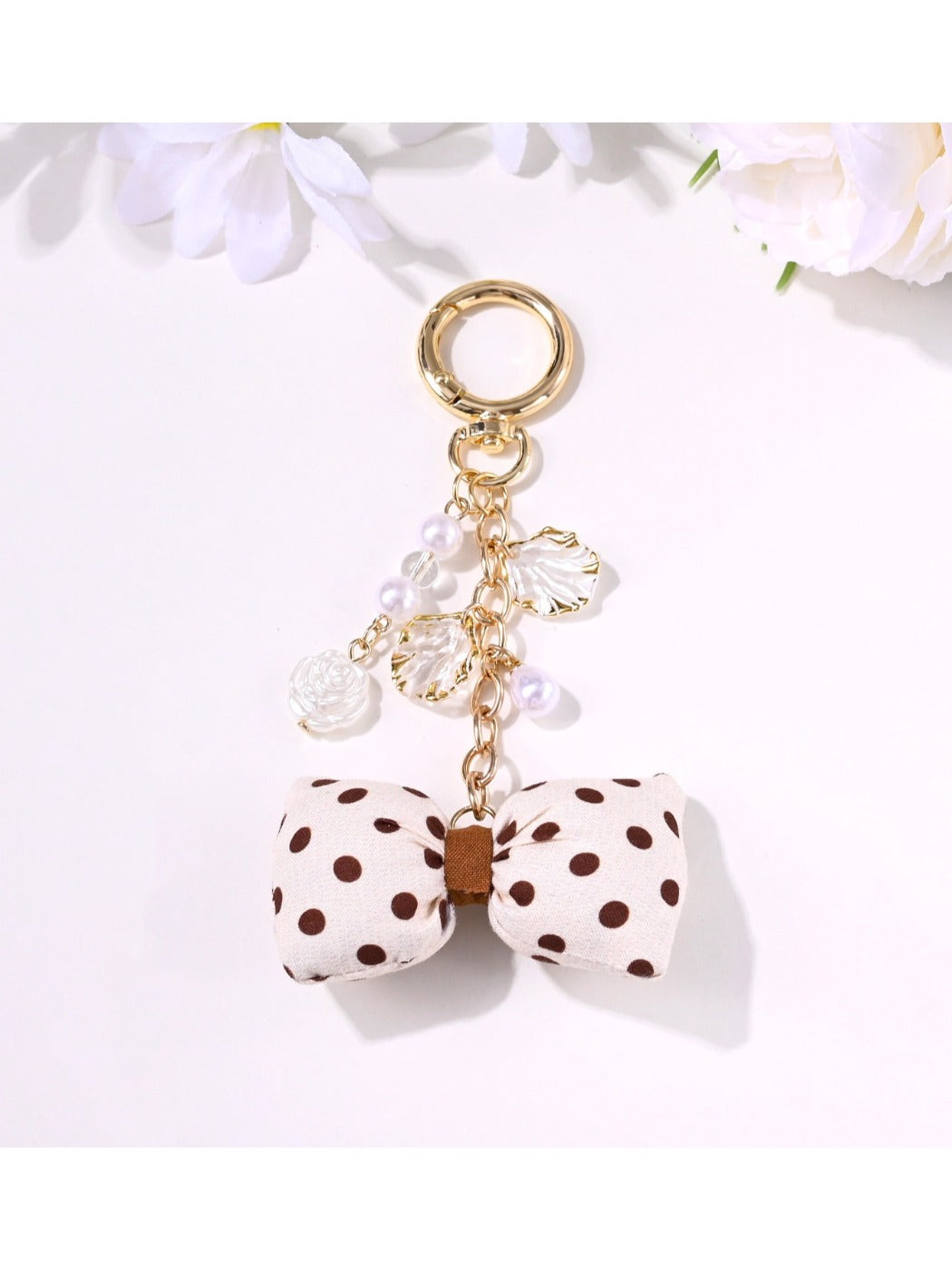 Close-up of a rose-shaped pendant keychain in soft pink with a gold keyring
