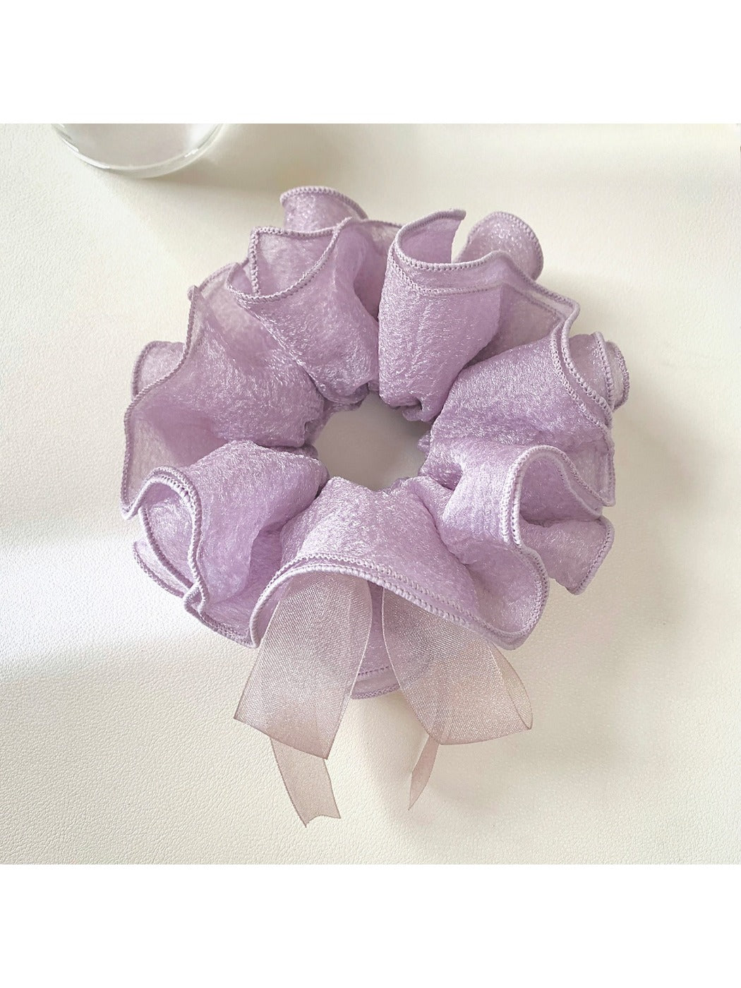 Purple bow scrunchie displayed flat with bow spread out on a white surface