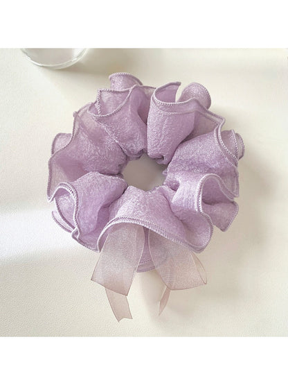 Purple bow scrunchie displayed flat with bow spread out on a white surface